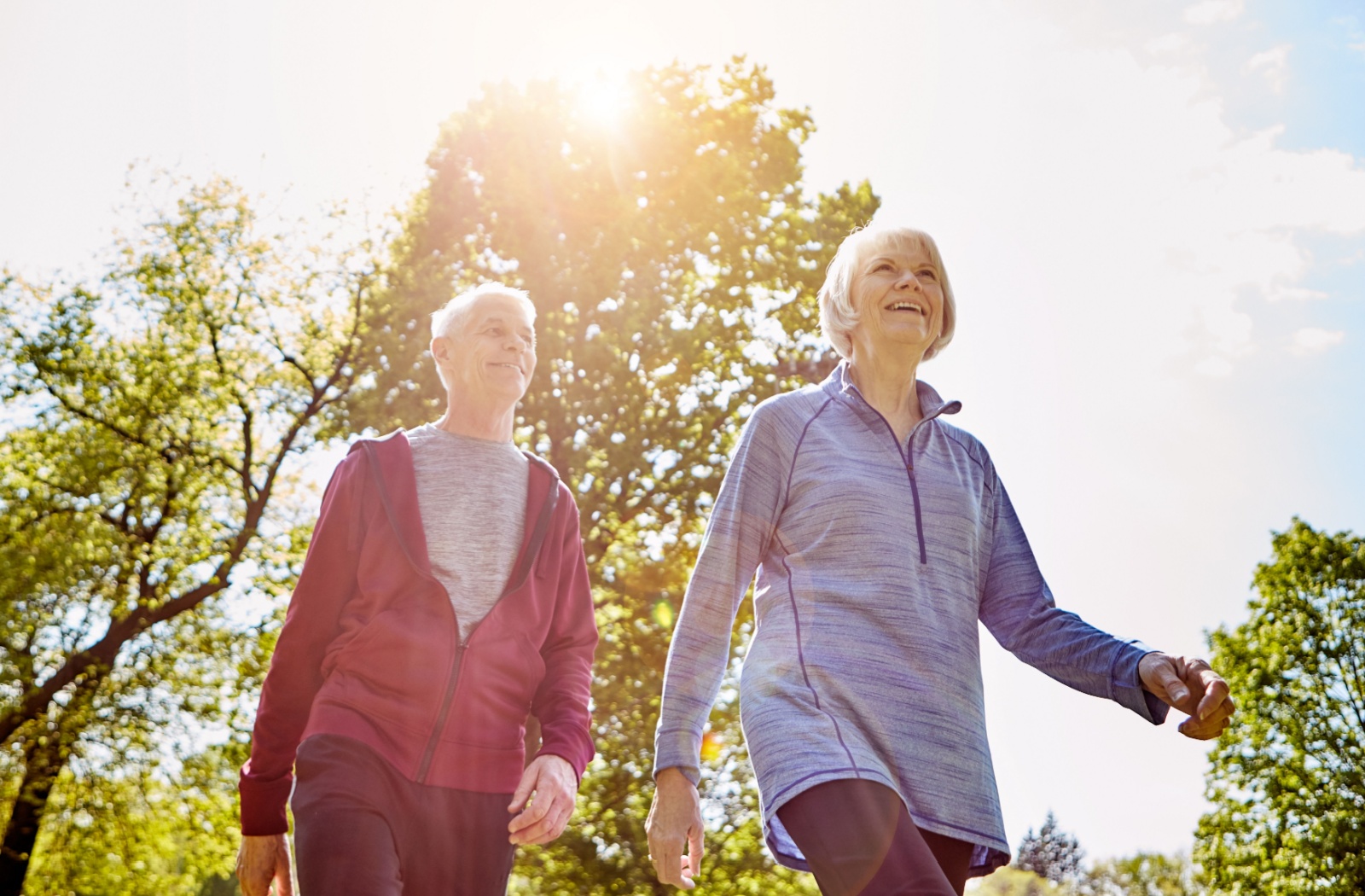 A smiling senior couple walking together and enjoying a beautiful sunny day.