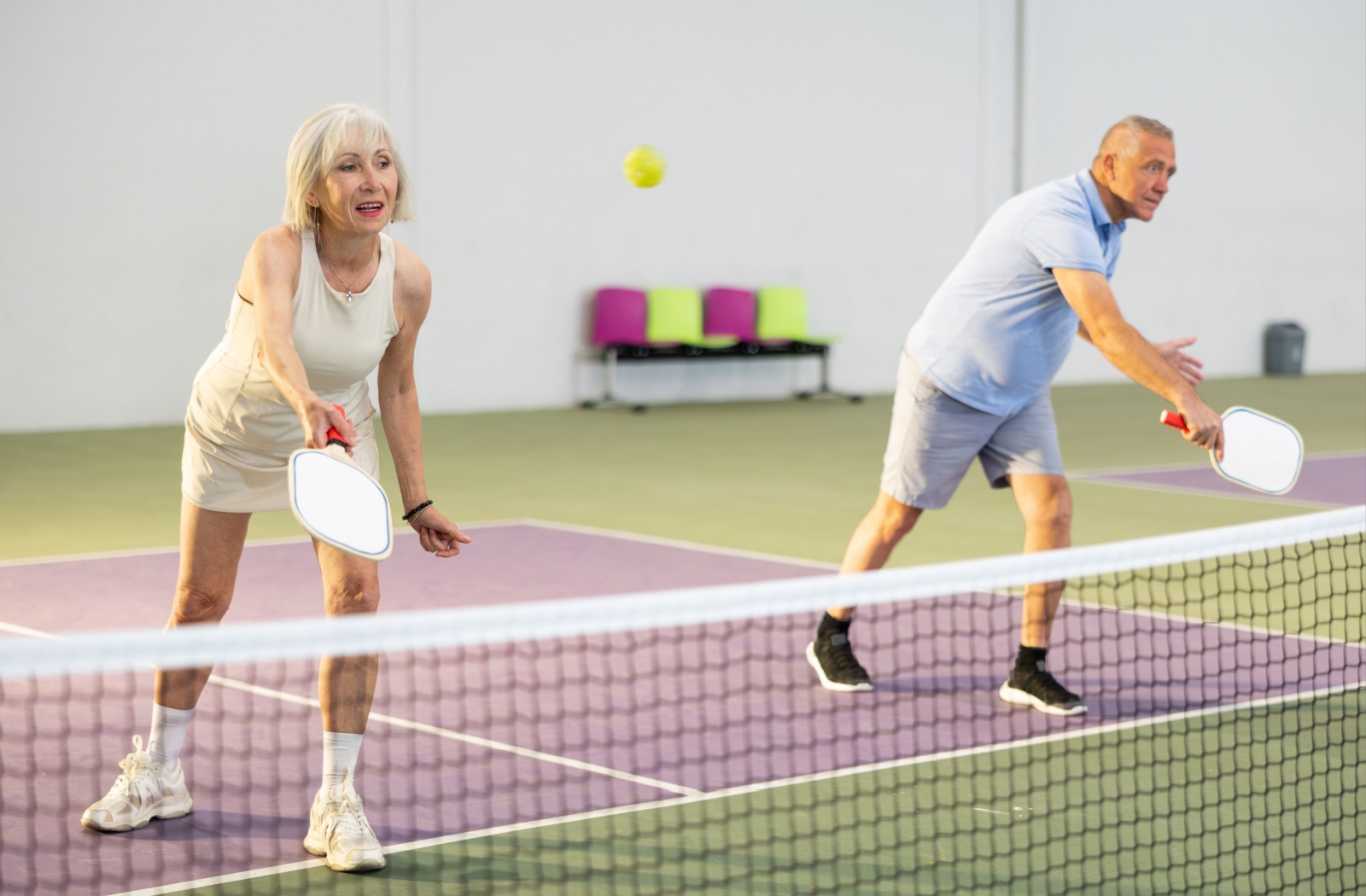 A pair of active older adults play pickleball together.
