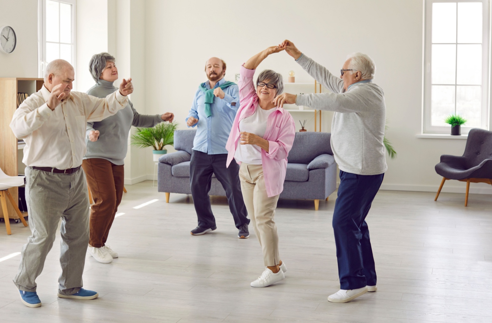 A group of residents enjoy dancing together in their senior living community.
