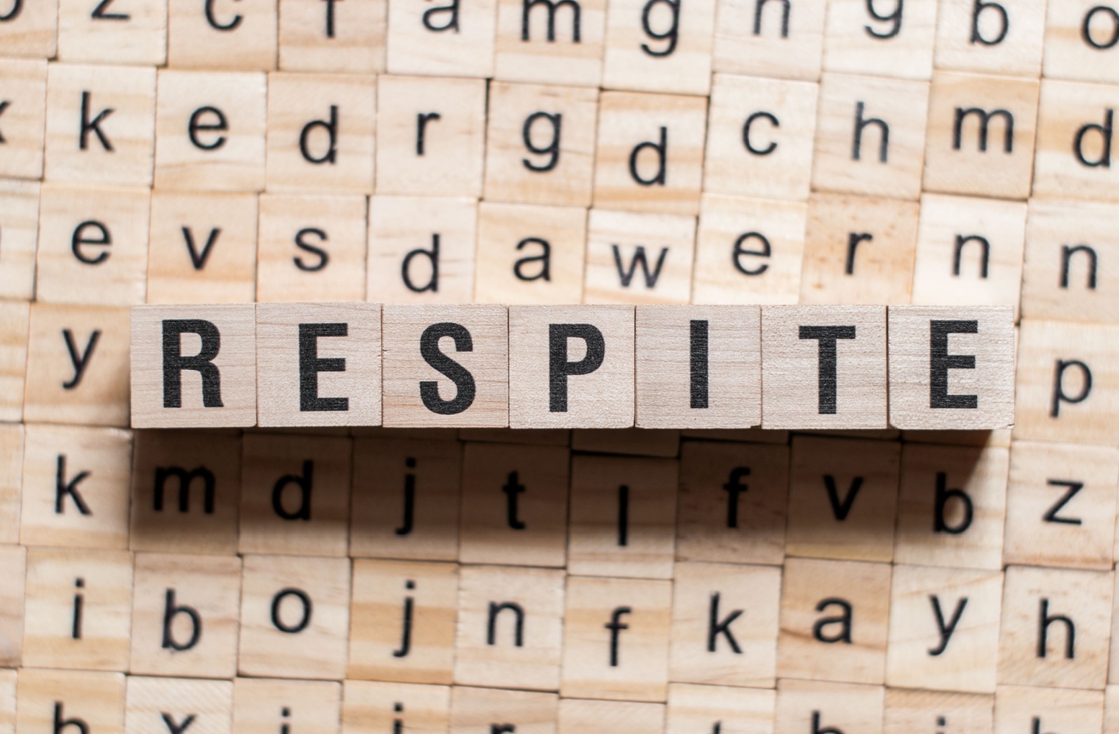 a variety of letters in the background with 'respite' spelled in the foreground.