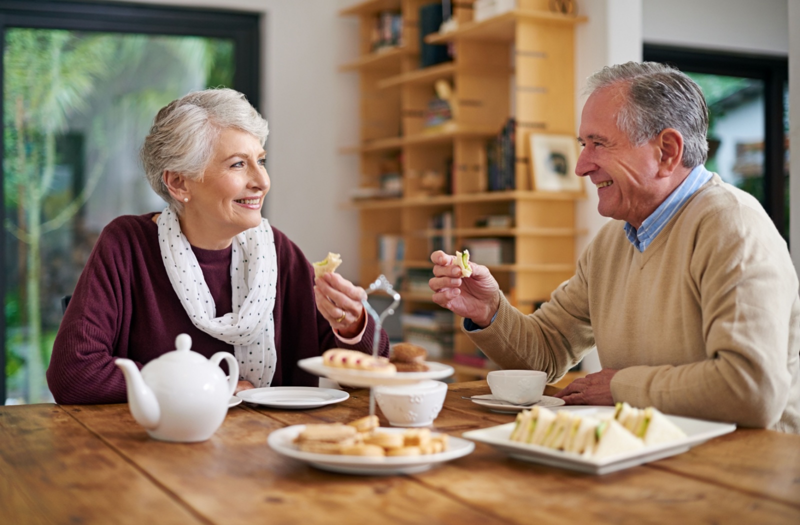 Senior couple enjoys tea & finger sandwiches in an independent living home.