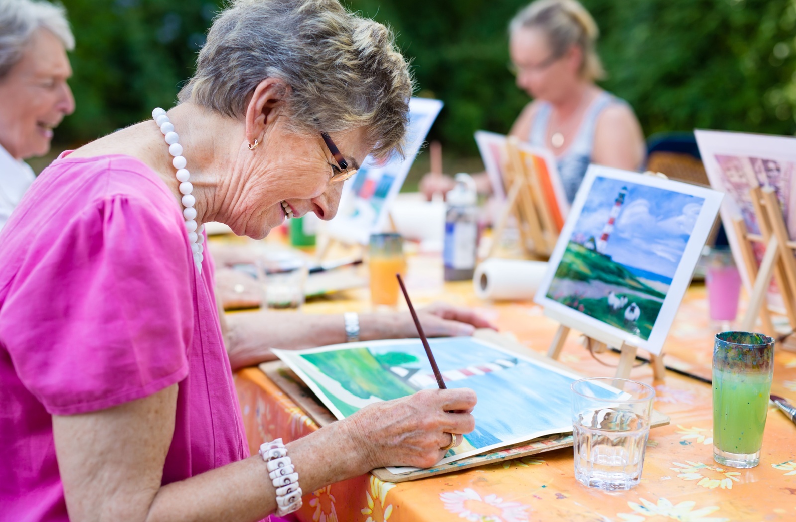 A group of retired older adults sitting outdoors during a watercolor painting class and laughing.