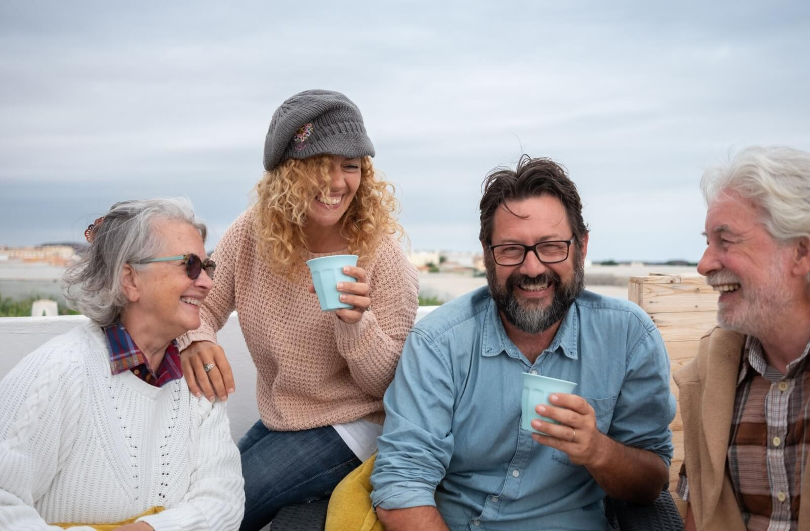 Older adults and younger friends laugh together while sharing drinks highlighting the joy of social interaction for seniors
