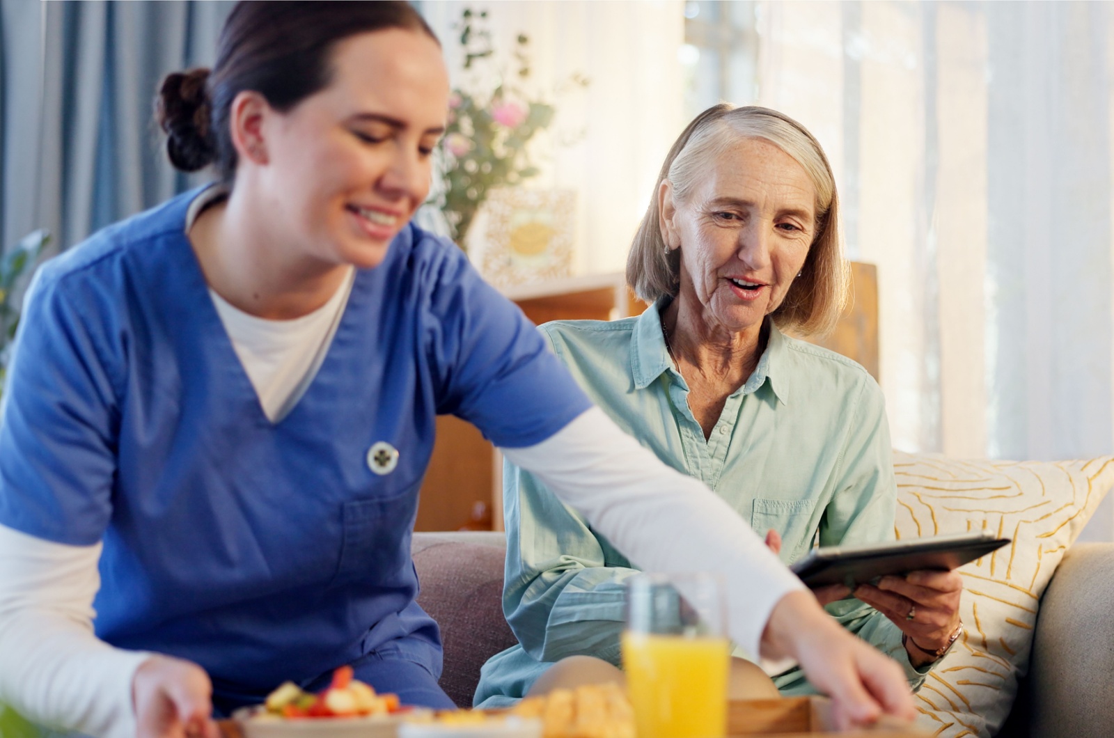 An assisted living caregiver serves breakfast to a resident.