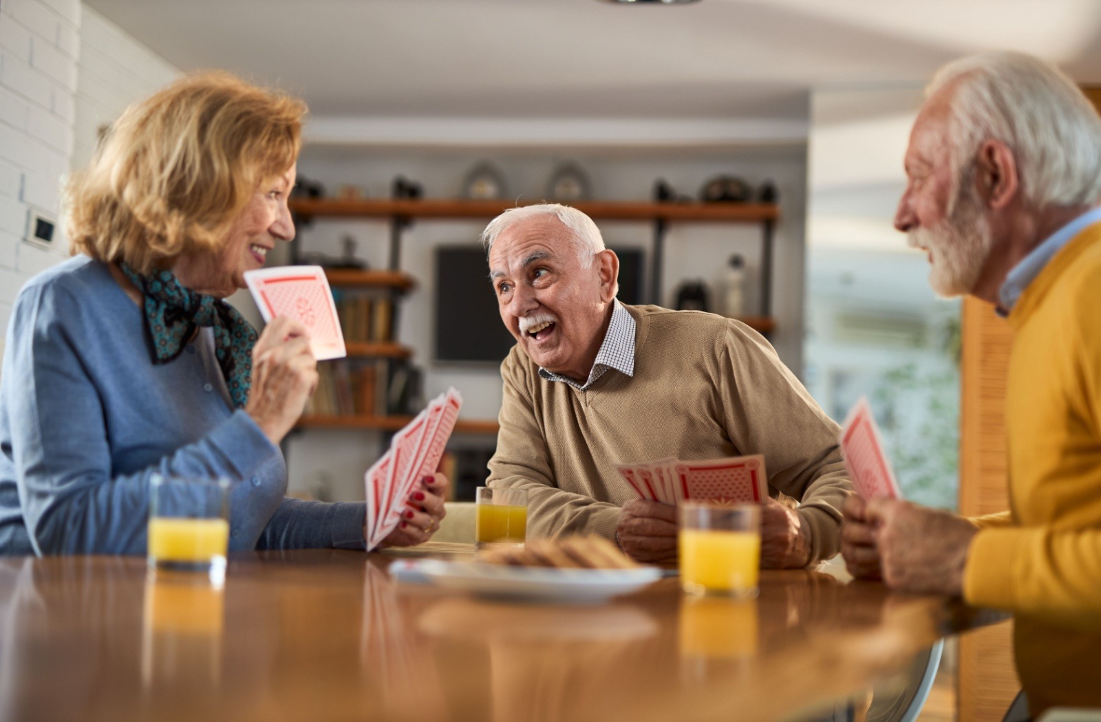 A group of seniors play a game of cards while having breakfast together.
